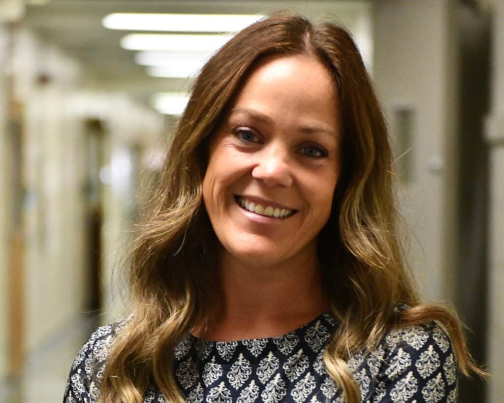 A smiling woman standing in a hallway.