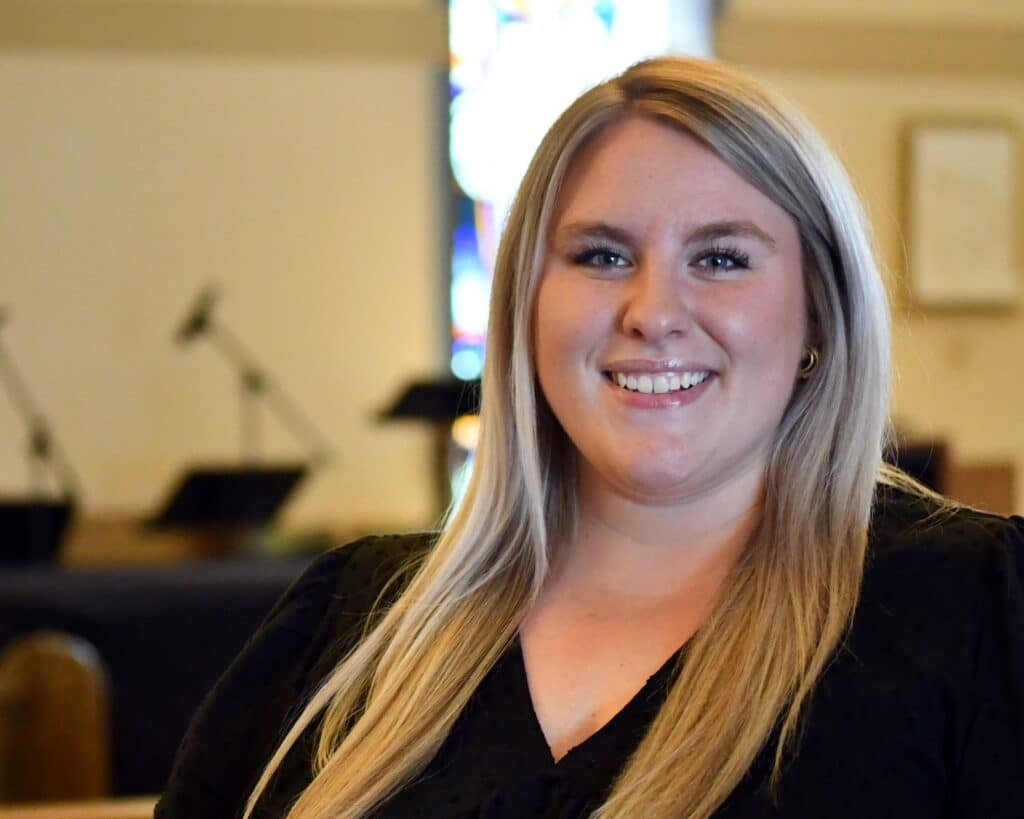 A woman smiling in a church pew.