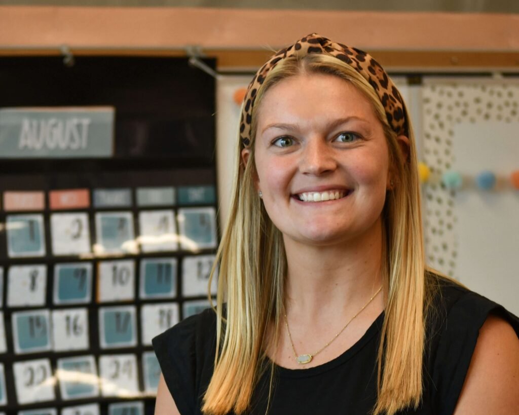 A woman smiling in front of a bulletin board.