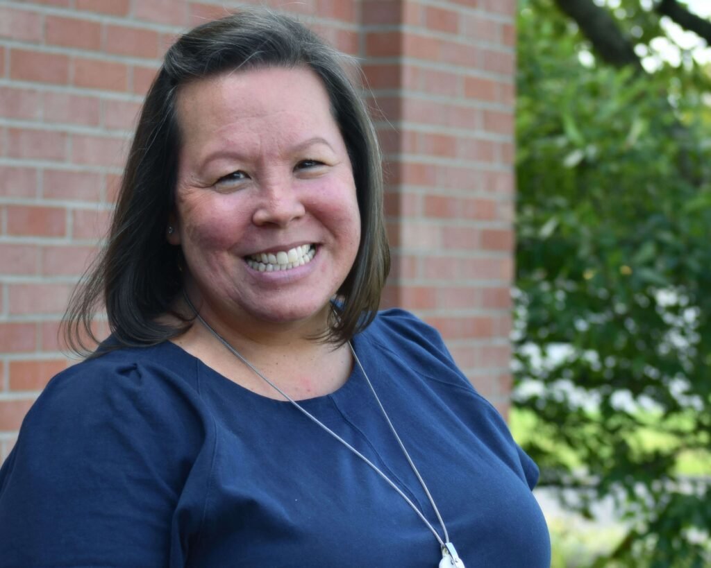 A woman smiling in front of a brick wall.