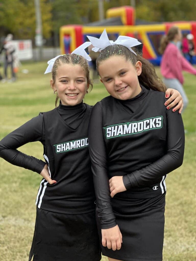 Two girls posing for a photo in a cheerleading uniform.