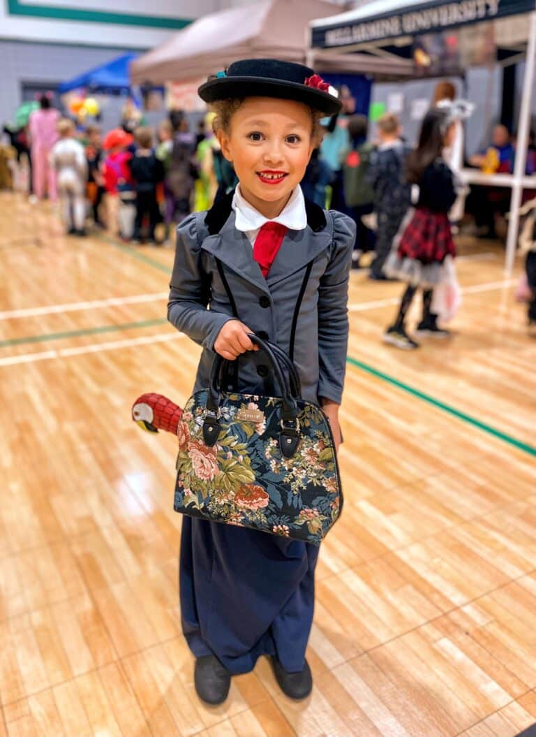 A little girl in a costume holding a purse.